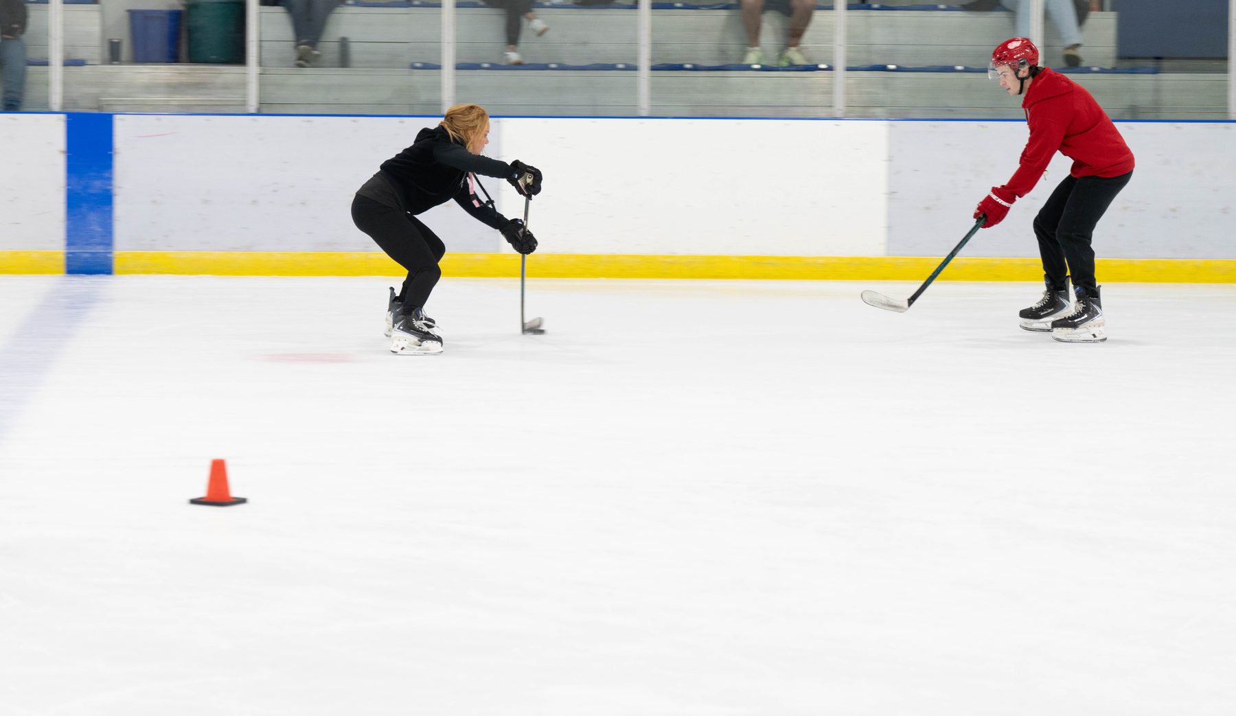 Stacy Allen working one-on-one with a player in a red helmet on open ice